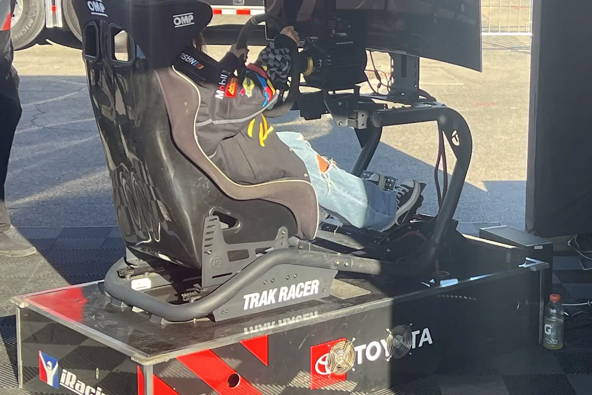 Trak Racer sim racing cockpit with racing seat and triple screens on a display stand